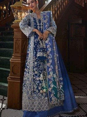 Royal blue heavily embroidered ensemble with silver thread work, shot on a wooden staircase.
